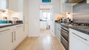 Cocina moderna con armarios blancos, estufa de acero inoxidable y encimera negra.