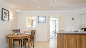 A modern kitchen with a wooden dining table, chairs, and a built-in island with a countertop. - Lantern Suite, Holiday Apartment Tenby, Pembrokeshire, Sleeps 2, 1 bedrooms,  bathrooms (Tenby)