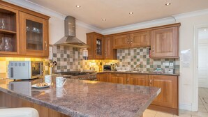 A modern kitchen with granite countertops, wooden cabinets, and stainless steel appliances. - Lantern Suite, Holiday Apartment Tenby, Pembrokeshire, Sleeps 2, 1 bedrooms,  bathrooms (Tenby)