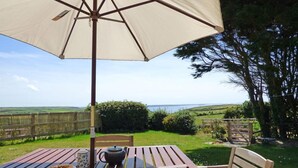 A wooden table with a beige umbrella, a plate with food, and a teapot. - Little Folly, Holiday Cottage Nolton Haven, Sleeps 4, 2 bedrooms,  bathrooms (Haverfordwest)