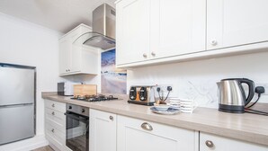 A modern kitchen with white cabinets, a built-in oven, a gas stove, a toaster, and a kettle. - Little Mead, Holiday Cottage Amroth, Sleeps 4, 2 bedrooms,  bathrooms (Amroth)
