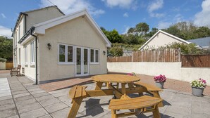 A house with a patio featuring a wooden table and benches. - Little Mead, Holiday Cottage Amroth, Sleeps 4, 2 bedrooms,  bathrooms (Amroth)