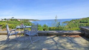 A patio with a table and chairs overlooking a coastal landscape. - Little Pentower, Holiday Apartment Fishguard, Sleeps 2, 1 bedrooms,  bathrooms (Fishguard)