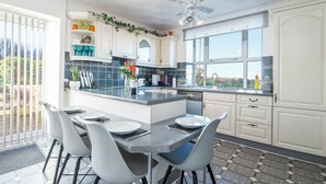 A modern kitchen with white cabinets, a granite countertop, and a dining area with a table and chairs. - Llwyndyrys, Holiday Cottage Square and Compass, Sleeps 4, 2 bedrooms,  bathrooms (Haverfordwest)