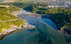Vue aérienne d’une ville côtière avec un port de plaisance, des bateaux et une route menant au centre-ville.