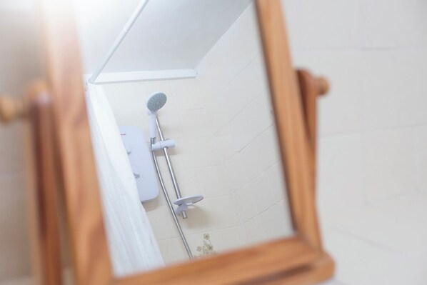 Une salle de bain avec une douche, des toilettes et un miroir.