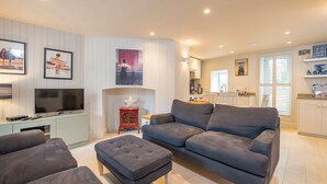 A modern living room with a grey sofa, a television, and framed artwork on the wall. - Lower Deck, Holiday Apartment Tenby, Sleeps 2, 1 bedrooms,  bathrooms (Tenby)