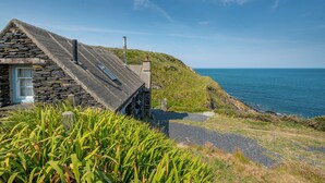 Une maison en pierre, avec un toit en pente, qui offre une vue sur la côte.