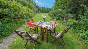 A wooden table with four chairs, a bench, and a pathway leading to a garden. - Middle Hill Cottage, Holiday Cottage Amroth, Sleeps 4, 2 bedrooms,  bathrooms (Amroth)