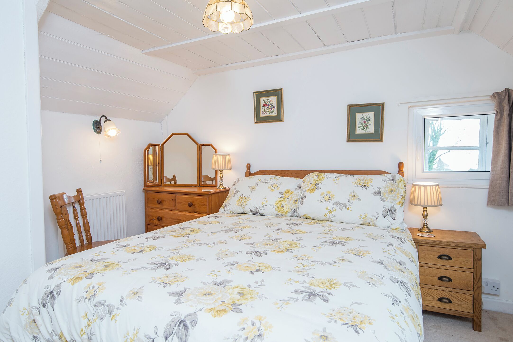A bedroom with a large bed, wooden nightstands, a dresser, and a window with curtains.