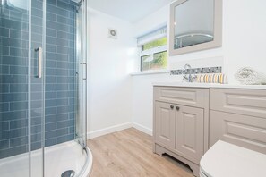 Une salle de bain moderne avec une douche à parois de verre, un lavabo blanc agrémenté d’une serviette à rayures et un meuble-lavabo beige.