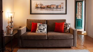 A living room with a sofa, red cushions, a framed cityscape picture, a lamp, and a decorative door. - Como Lake Panorama apartment Sveva with fireplace and private terrace (Cernobbio)