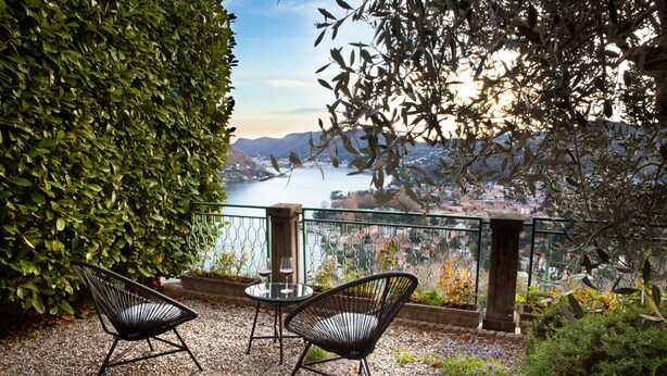 A terrace with two wicker chairs and a table, overlooking a body of water and a cityscape. - Como Lake Panorama apartment Sveva with fireplace and private terrace (Cernobbio)