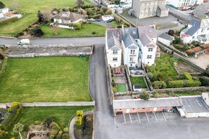 Residential area with a building featuring a pitched roof and multiple windows, surrounded by well-maintained lawns and a parking area.