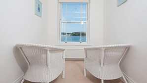 A room with two white wicker chairs facing a window overlooking a body of water. - Musselwick House, holiday property St Ishmaels, Near Dale, Sleeps 8, 4 bedrooms,  bathrooms (Haverfordwest)