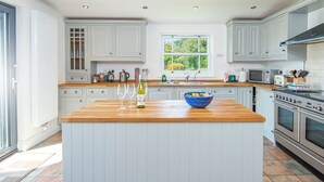 A kitchen with white cabinets, a wooden countertop, a blue bowl, wine glasses, and a stove. - Musselwick House, holiday property St Ishmaels, Near Dale, Sleeps 8, 4 bedrooms,  bathrooms (Haverfordwest)