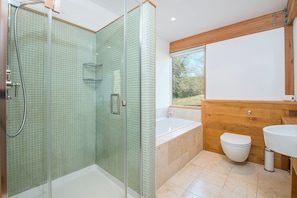 Ein modernes Badezimmer mit Duschkabine aus Glas, freistehender Badewanne, Toilette und Waschbecken.