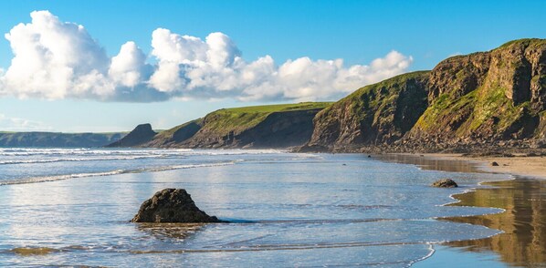 A coastal landscape with cliffs, a beach, and waves.