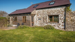 A stone house with a wooden extension, a fenced yard, and a clear sky. - Nolton Coach House, Holiday Cottage Nolton Haven, Sleeps 2, 1 bedrooms,  bathrooms (Haverfordwest)