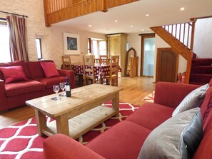A living room with a red sofa, a wooden table with wine glasses, and a staircase.