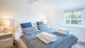 Un dormitorio con cama, dos mesitas de noche, una ventana y vistas al exterior.
