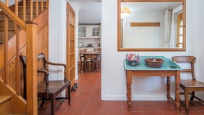 Uma escada de madeira leva a uma área de cozinha com uma mesa e cadeiras.