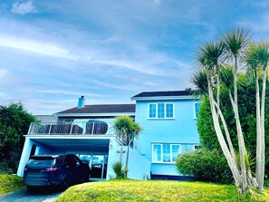 A two-story house with a garage, a covered driveway, and a well-maintained lawn. - Pine Lodge, Holiday Home Wisemans Bridge, Pembrokeshire, Sleeps 12, 5 bedrooms,  bathrooms (Narberth)