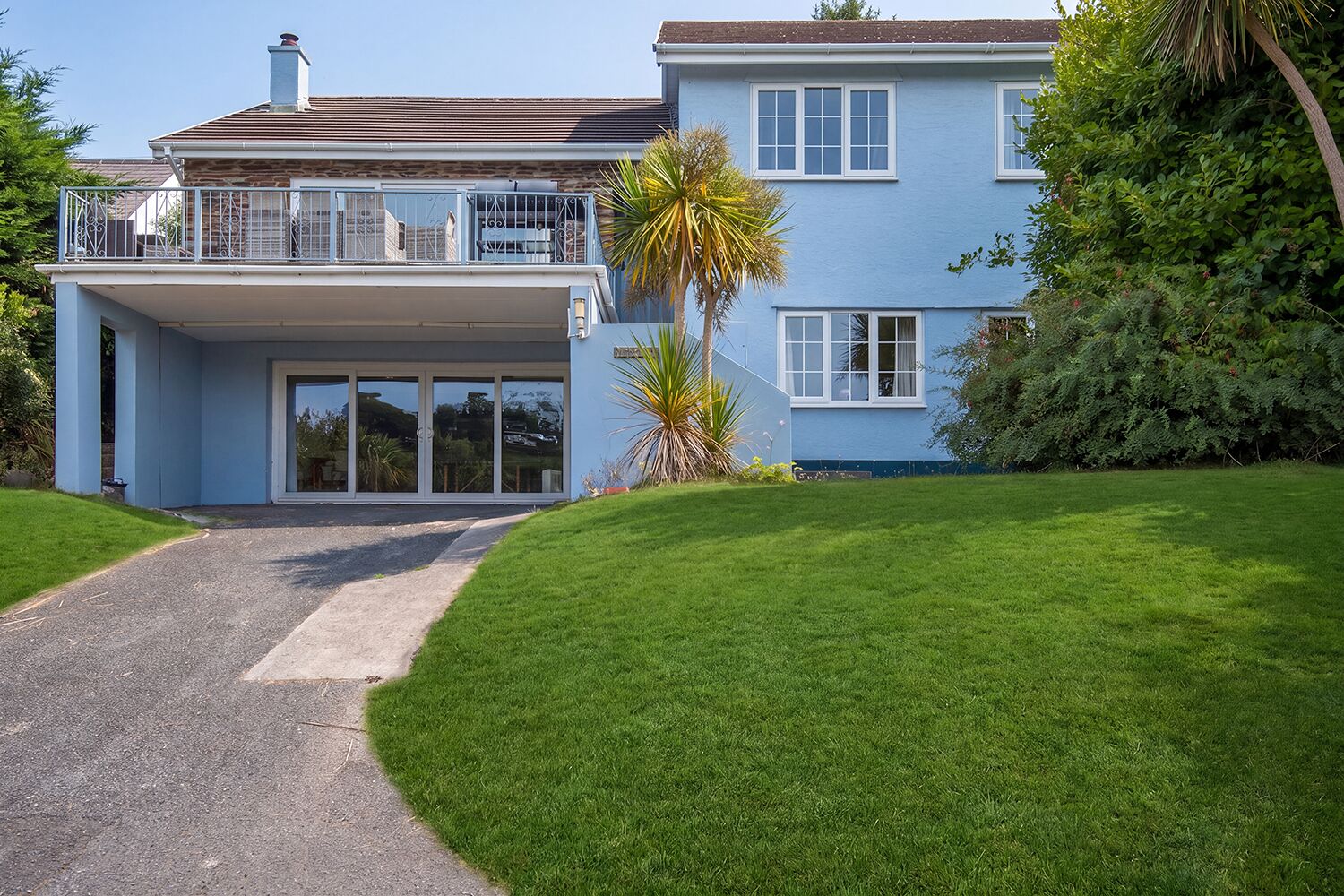 A two-story house with a covered entrance and a paved driveway leading to the front door.