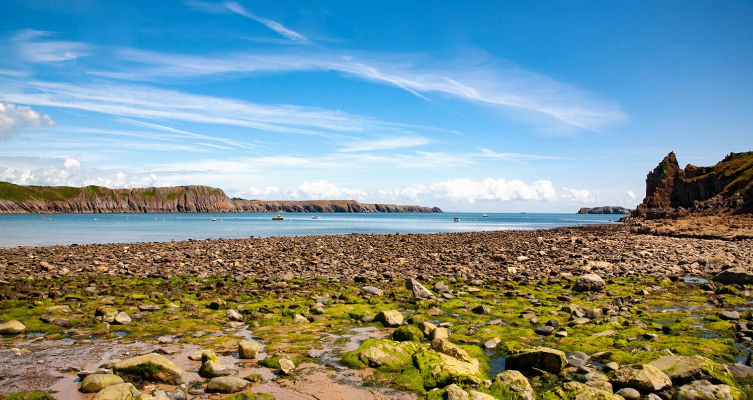 A rocky beach with a clear sky and calm sea.