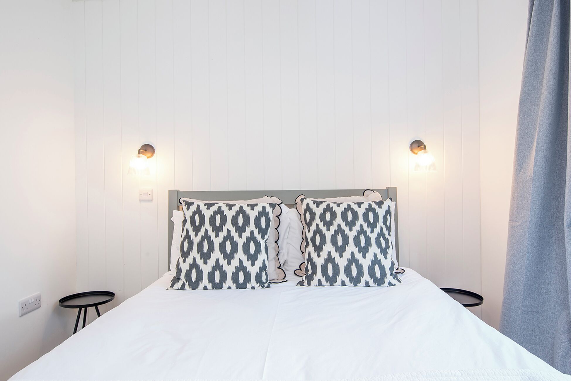 Una habitación de hotel con cama, dos lámparas de pared y una mesita redonda.
