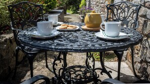 A round metal table with a tea set, two white cups, and a plate of biscuits. - Salar, Holiday Cottage Lawrenny, Sleeps 4, 2 bedrooms,  bathrooms (Lawrenny)