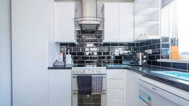 A modern kitchen with white cabinets, a stainless steel range hood, a built-in oven, and a dishwasher. - Sandgrove, Holiday Home Saundersfoot, Sleeps 4, 2 bedrooms,  bathrooms (Saundersfoot)