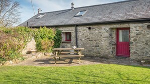 A stone building with a red door, a small window, and a picnic table in the yard. - Seahorse Cottage, Holiday Cottage Aberfforest Beach, Newport, Sleeps 6, 3 bedrooms,  bathrooms (Newport)