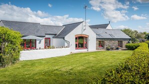 A two-story house with a stone exterior, red-framed windows, and a sloped roof. - Silk Purse, Holiday Home Angle, Sleeps 4, 2 bedrooms,  bathrooms (Angle)