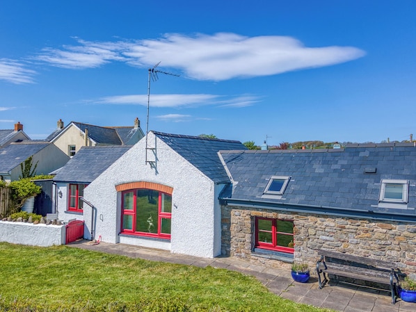 A house with a sloped roof, stone walls, and a red door.