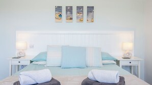 A bedroom with a bed, two bedside tables, a nightstand, a headboard, and three wall-mounted paintings. - Silk Purse, Holiday Home Angle, Sleeps 4, 2 bedrooms,  bathrooms (Angle)