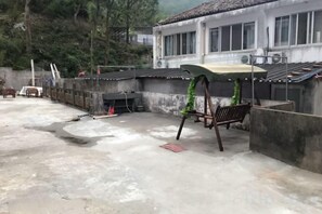 Una terraza en la azotea con piso de concreto, una mesa pequeña y un banco.