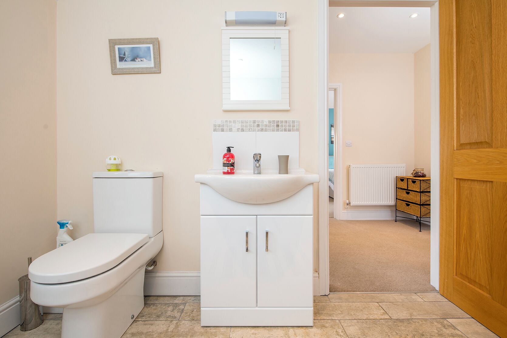Ein Badezimmer mit Toilette, Waschbecken mit Spiegel und Heizkörper.