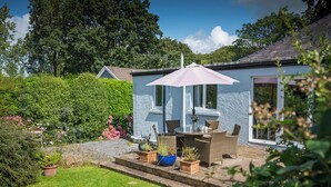 A house with a patio, outdoor furniture, and a garden.