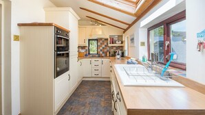A modern kitchen with white cabinetry, a built-in oven, and a skylight. - Sunnybank, holiday property Manorbier, Sleeps 6, 3 bedrooms,  bathrooms (Manorbier)