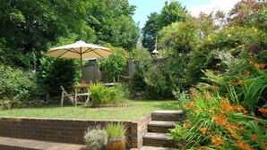 Une terrasse aménagée avec une table et des chaises, un mur en briques et une clôture en bois.