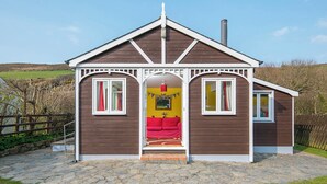 A cozy cabin with a stone-paved entrance, a red sofa inside, and a chimney. - Swn y Mor, Holiday Apartment Pwllgwaelod, Sleeps 4, 2 bedrooms,  bathrooms (Dinas)
