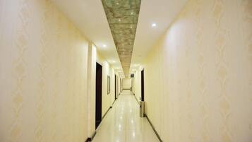 A long, narrow hotel corridor with patterned walls and a tiled floor.