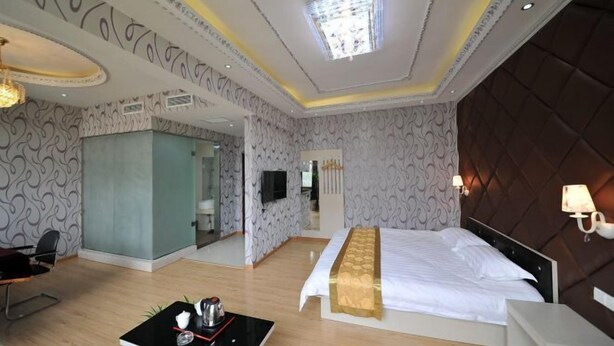 Une chambre d’hôtel avec un grand lit, un bureau avec une bouilloire, une télévision et un miroir.