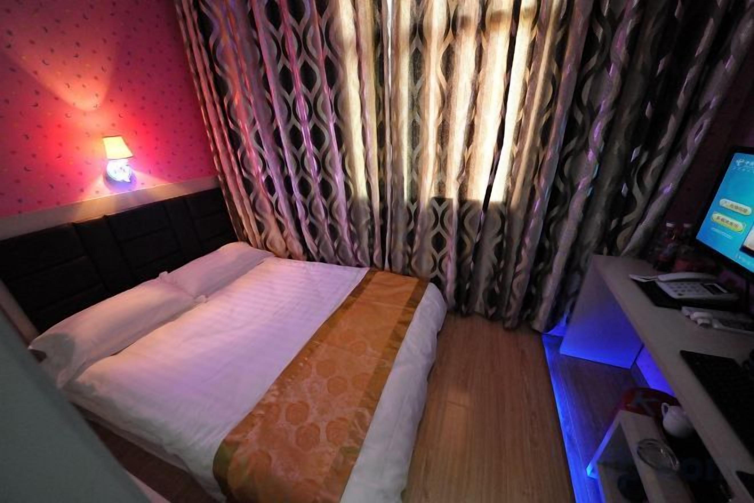 Una habitación de hotel con cama, un escritorio con computadora y una lámpara.