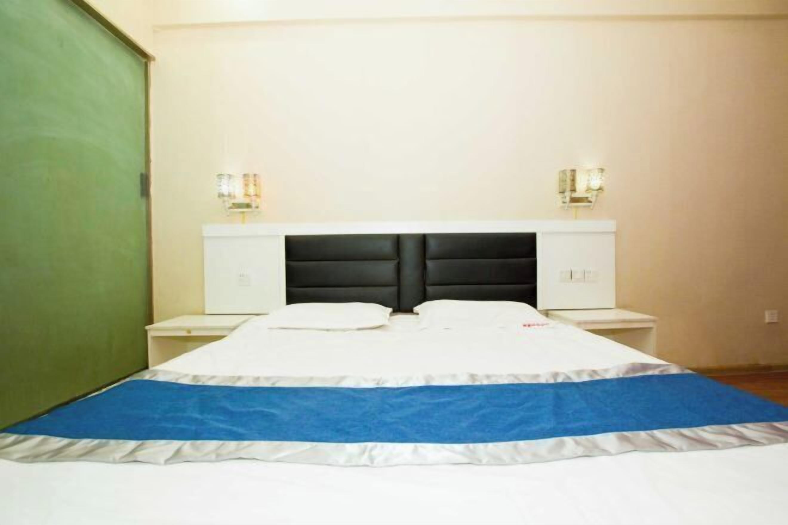 A bedroom with a bed, nightstands, and wall-mounted lamps.