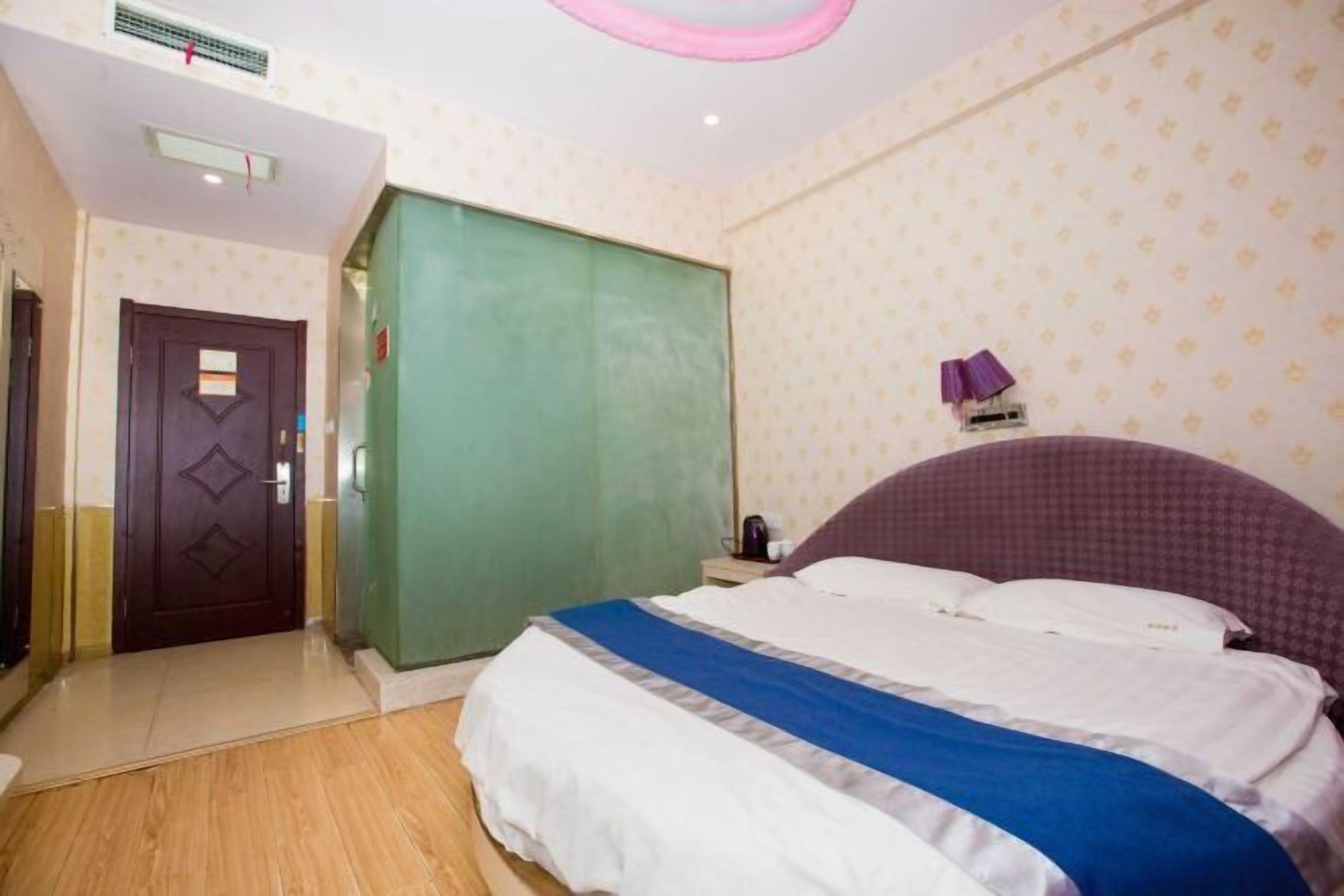 Un dormitorio con una cama, un armario, una puerta y una lámpara fijada a la pared.