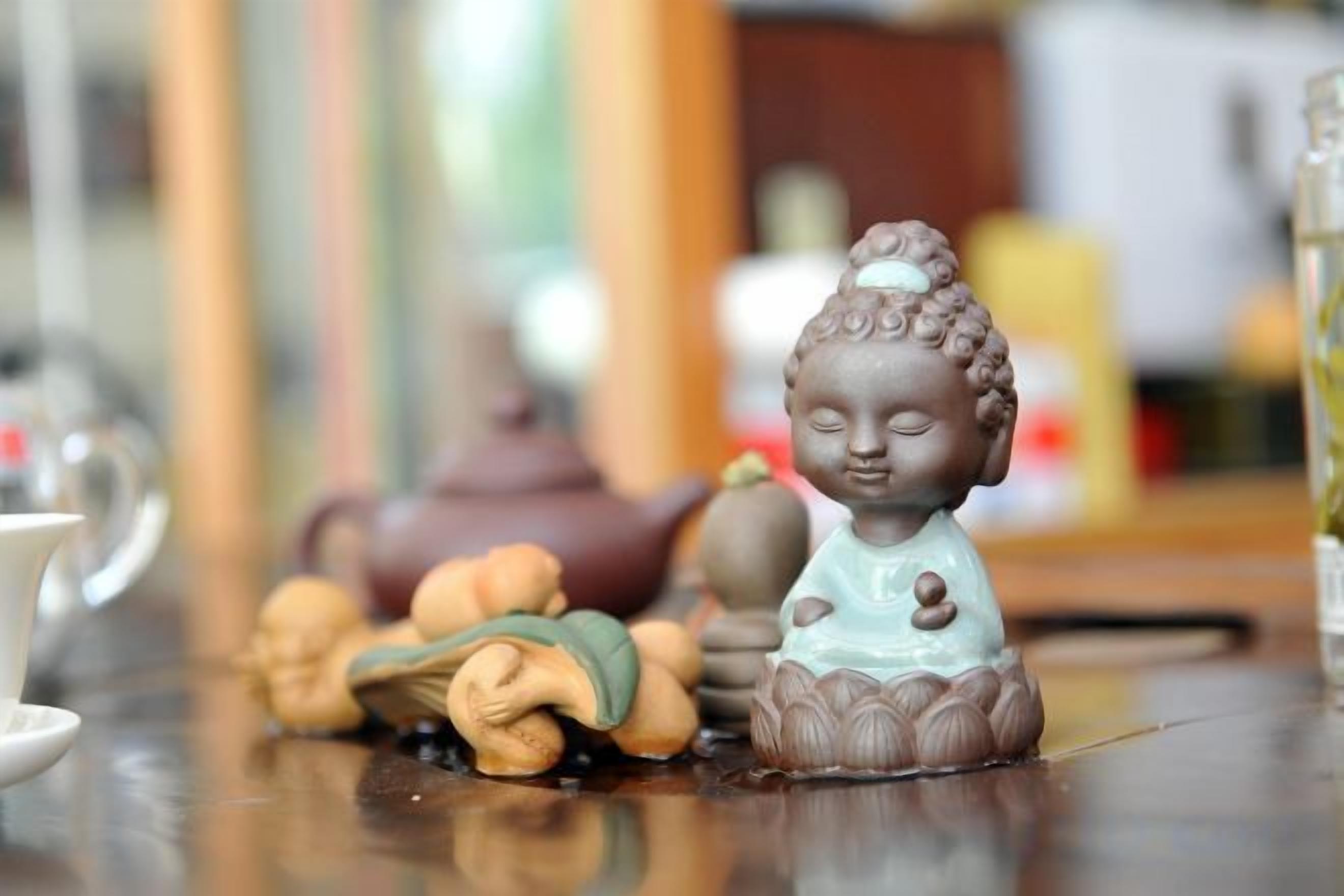 Una estatua de Buda sobre una mesa con una tetera y una taza.