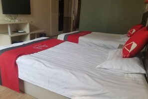 A hotel room with two beds, each with white bedding and red accents, a television on a shelf, and a door in the background. - AA Room (Suzhou)
