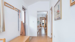 Ein Korridor mit Holzboden, einer Bank, einem Kleiderständer und einem gerahmten Bild an der Wand.